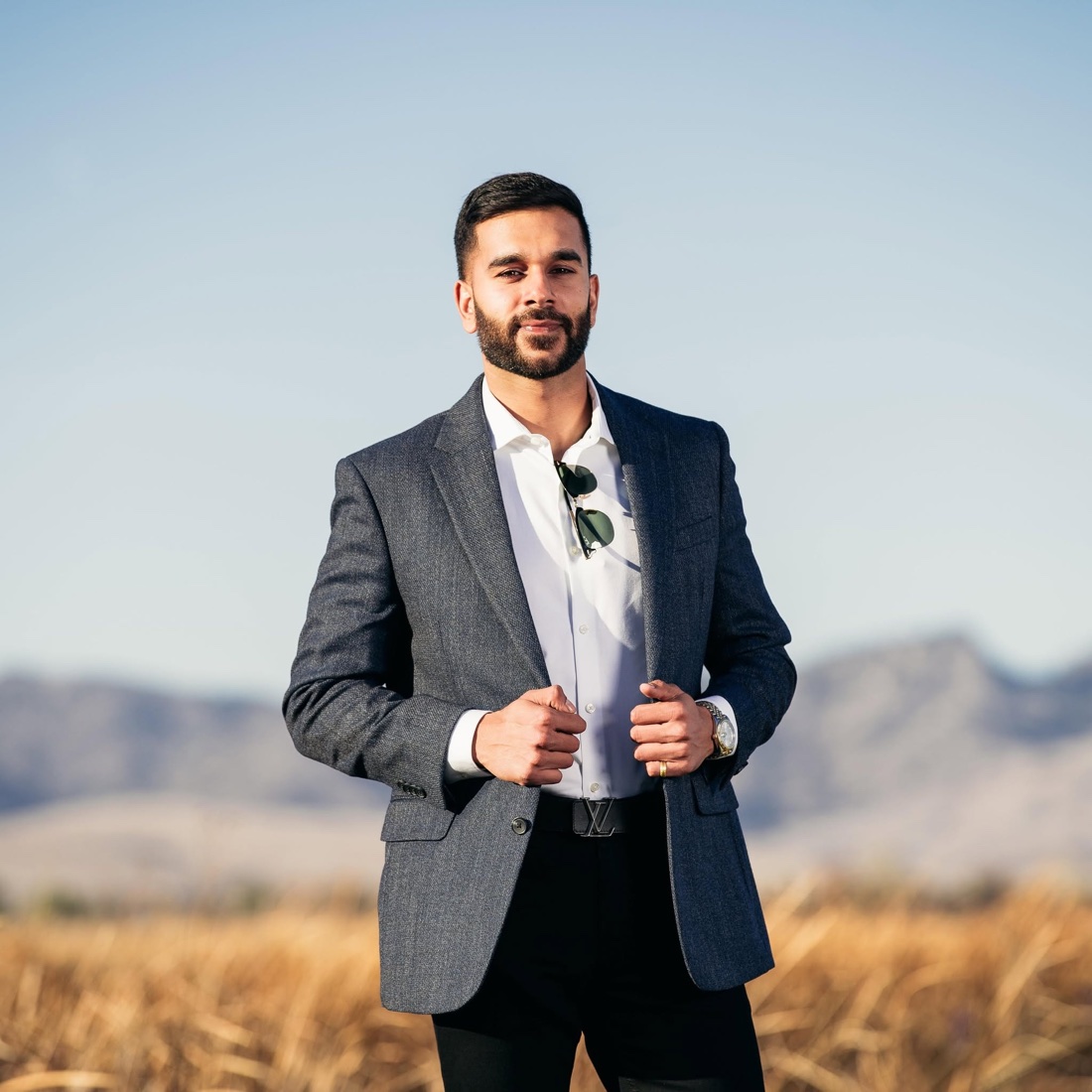 Sunny Purewal, owner and broker of Prospect Realty & Management, standing in a field with foothills behind